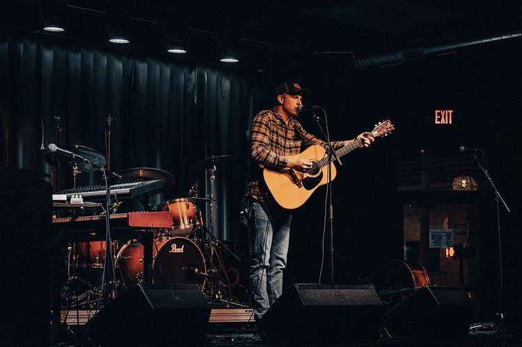 Jack Winders playing acoustic guitar on stage